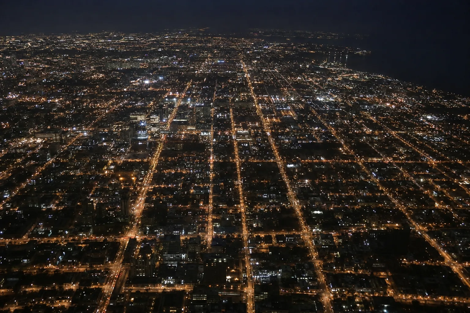 Abstract defocused night aerial of a city grid with warm streetlight glow