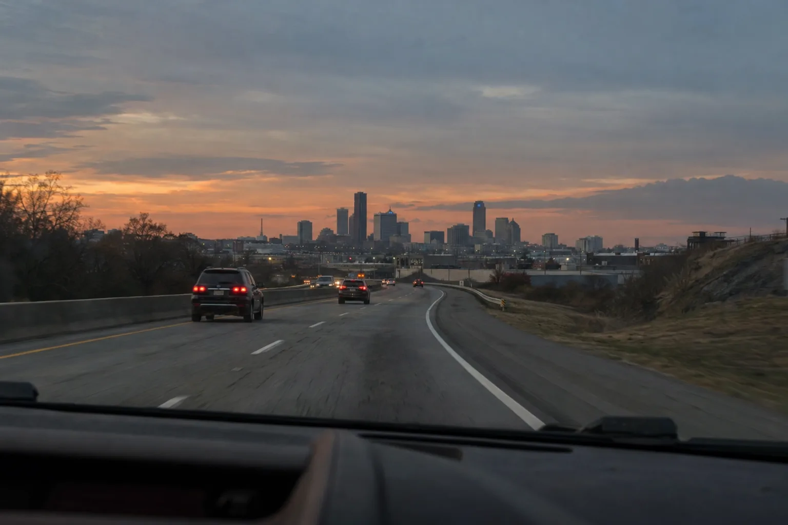 Dusk landscape with a winding road leading toward a distant city, warm low light