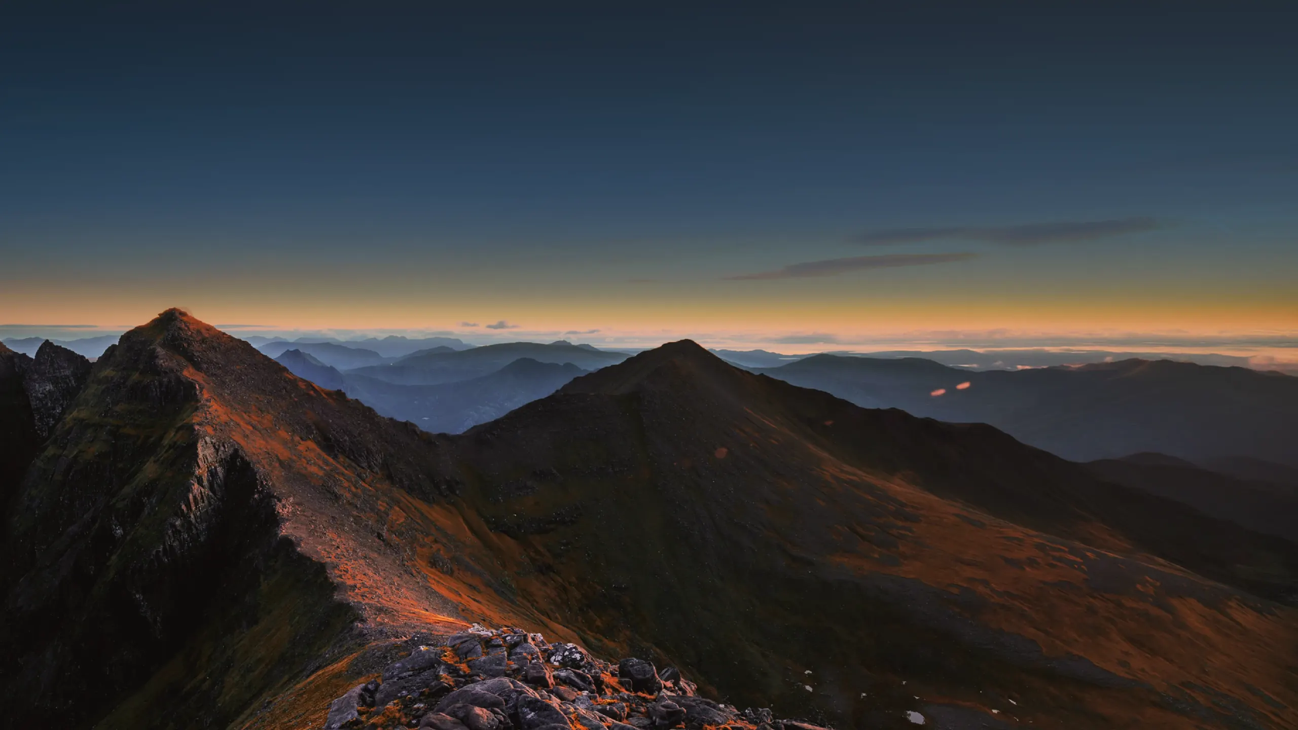 Mountain ridgeline at dusk under a deep blue sky